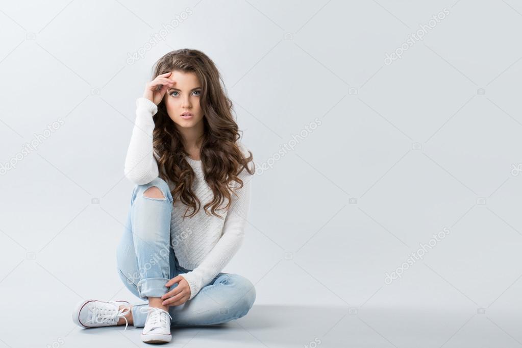 Young girl sitting in jeans and sneakers
