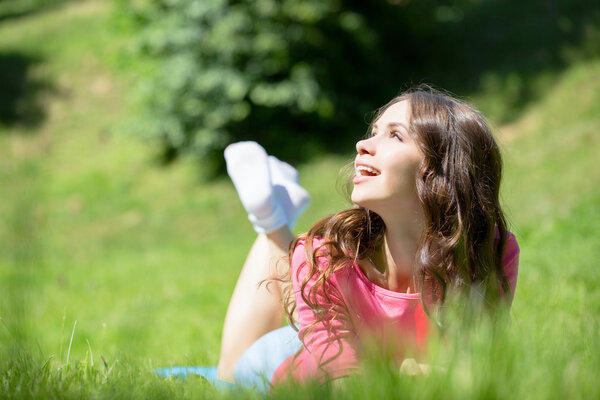 Женщина лежит в траве и улыбается
