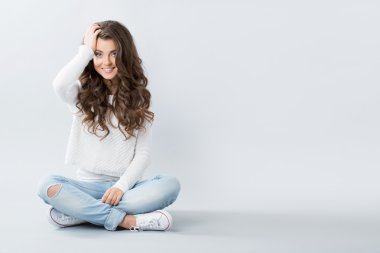 Güzel kız cross-legged katta oturan. 