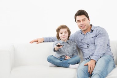 Baba ve oğul Tv uzaktan kumanda ile kanepede oturan.