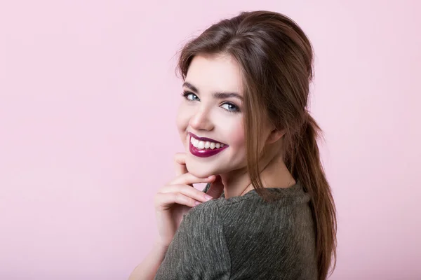 Retrato de menina atraente com lábios vermelhos em um fundo rosa . — Fotografia de Stock