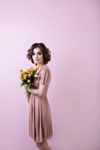 Retrato de uma jovem mulher em um vestido rosa com um buquê de flores — Fotografia de Stock