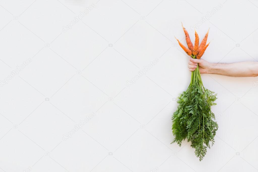Concept of healthy food. Farmer holding a carrot on a white background.