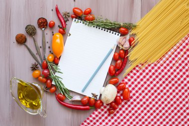 Baharatlar, makarna ve sebzeler defter çevresinde.