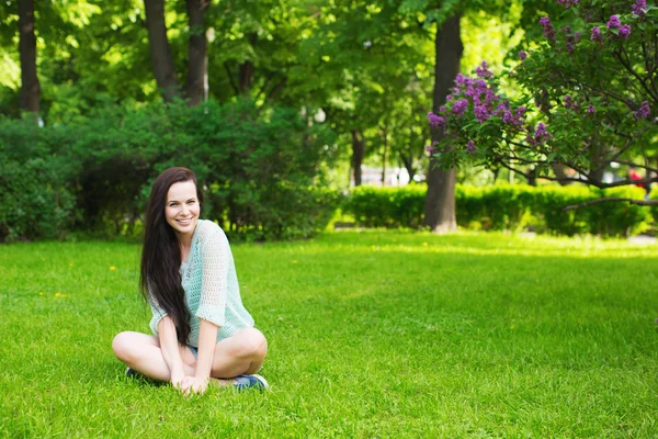 Studentka s úsměvem, sedět na trávě — Stock fotografie