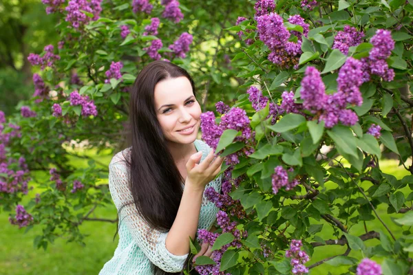 Menina cheirando as flores lilás — Fotografia de Stock