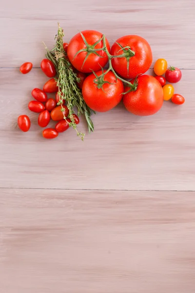 Tomates rojos frescos en una tabla de madera . — Foto de Stock