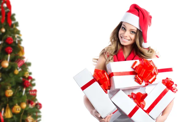 Retrato de una mujer de Navidad con regalos en sombrero de santa cerca del árbol de Navidad . — Foto de Stock