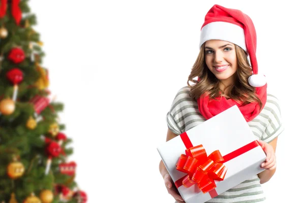 Hübsches Mädchen in Weihnachtsmützen mit einer Geschenkschachtel auf dem Hintergrund des Weihnachtsbaums. — Stockfoto