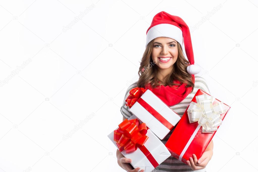 Cute girl holding a Christmas and New Year gifts. Christmas girl in santa hat with boxes.