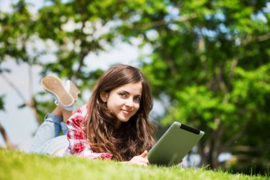 Güzel genç kadın açık havada touchpad ile.