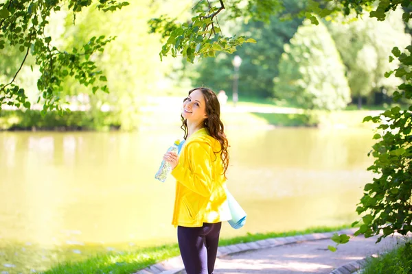 Χαμογελαστή γυναίκα με γιόγκα χαλάκι στο πάρκο. — Φωτογραφία Αρχείου