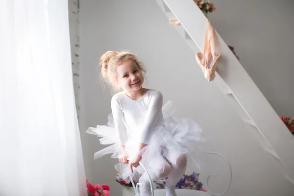 Little beautiful girl and pointe shoes near window. — Stock Photo, Image