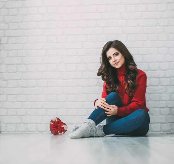 Schöne Frau in rotem Pullover und herzförmigem Geschenk. — Stockfoto