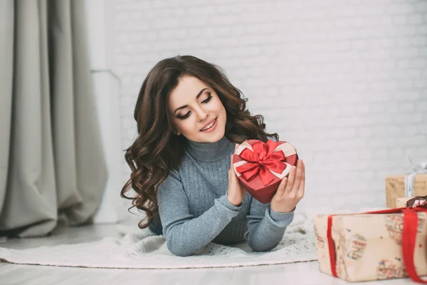 Hermosa morena mirando rojo regalo caja corazón . — Foto de Stock