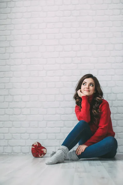 Dreamy woman in a red sweater and a heart shape gift. — Stock Photo, Image