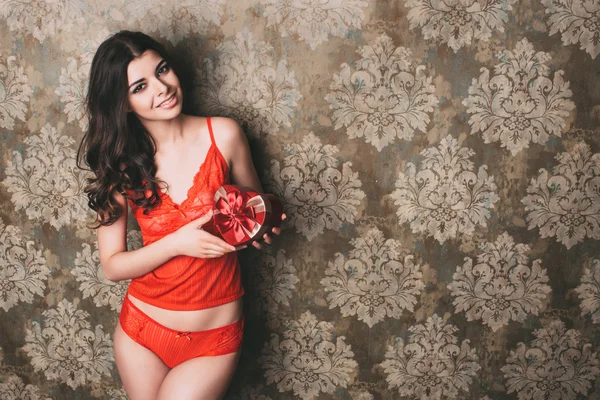 Beautiful woman in red lingerie holding gift box heart. — Stock Photo, Image