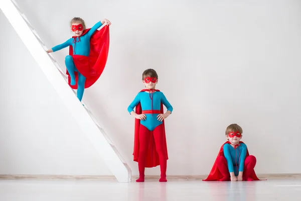 Niños jugando como superhéroes con abrigos rojos —  Fotos de Stock