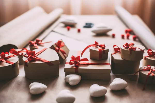 Κομψά δώρα με κόκκινη κορδέλα πάνω στο τραπέζι. — Φωτογραφία Αρχείου