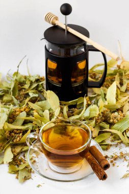 Close-up taken of dried linden leaves heap with a cup of tea and French Press on white background
