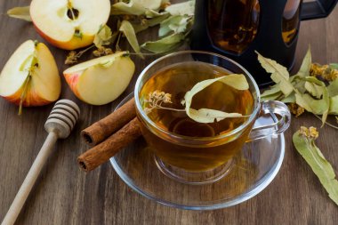 Fransız ezmesi, dilimlenmiş elma, doğal limon ve bal çubuğu ile ahşap masada kurutulmuş ıhlamur çayı.