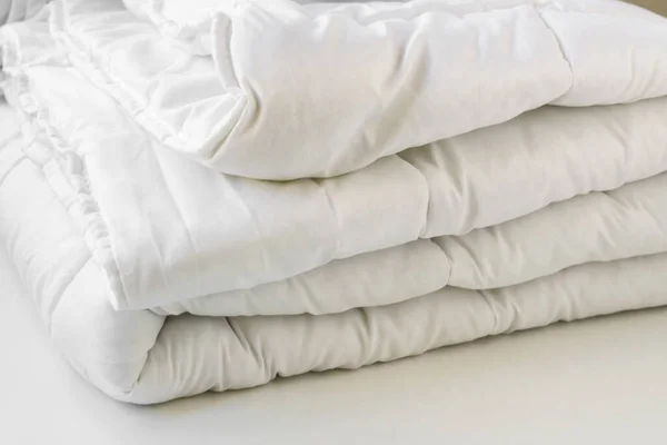 Yumuşak, beyaz, yıkanabilir çift katlı fiber yorgan beyaz arka planda yuvarlandı. Yakın plan alındı..
