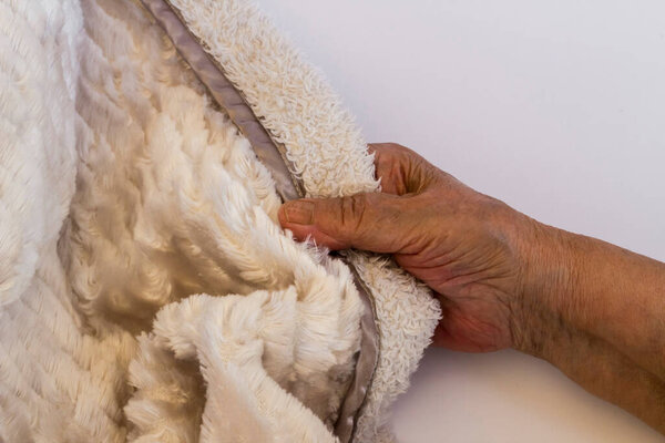 Softest plush blanket on white with old hand,close up