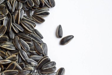 Taze, tuzsuz siyah ayçiçeği tohumları beyaz zemin üzerine dizayn edildi.