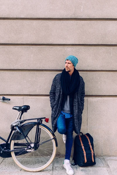 Homem esperando com sua bicicleta e saco em uma parede — Fotografia de Stock