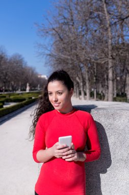 Telefonunu bir parkta tutan gülümseyen kadın