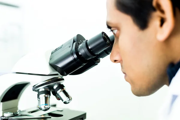 Un investigador concentrado trabajando con un microscopio en una bioquímica — Foto de Stock