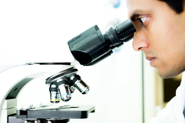 Un investigador concentrado trabajando con un microscopio — Foto de Stock