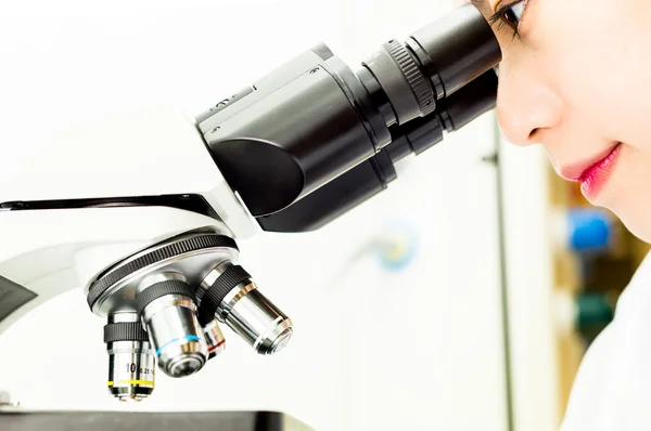 Investigador asiático mirando a través de una lente de microscopio — Foto de Stock