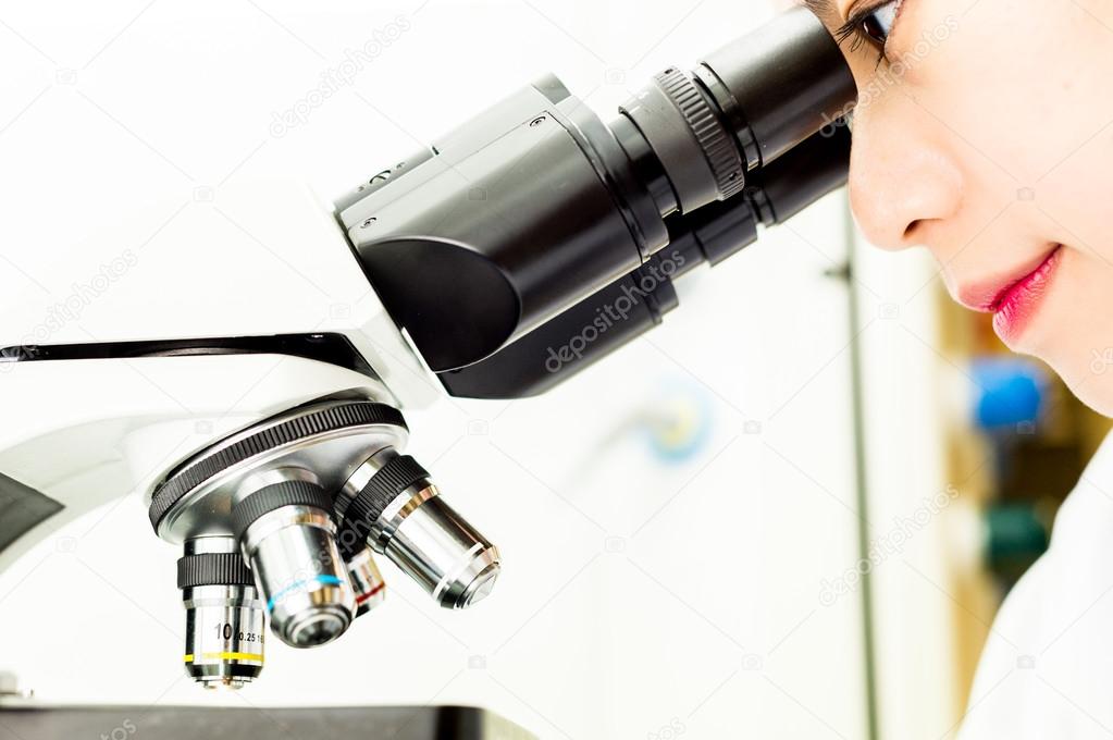 Asian Researcher looking through a Microscope Lens