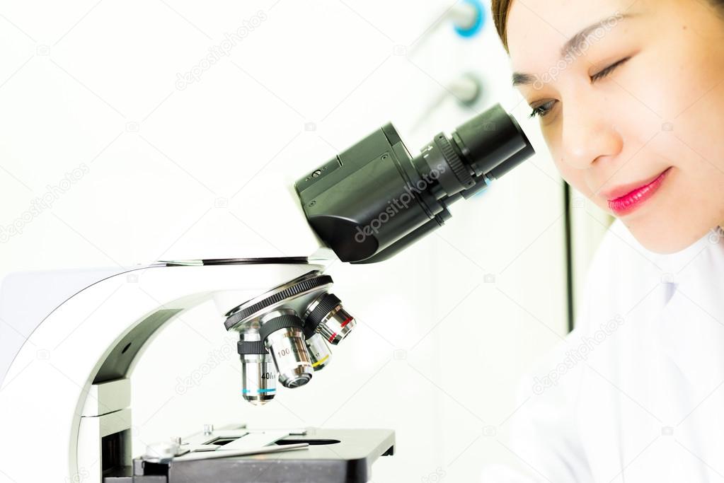 Asian Researcher looking through a Microscope