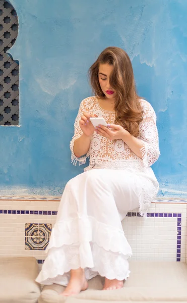 Bir bankta oturan ve onun telefon ile oynayan sevimli kız