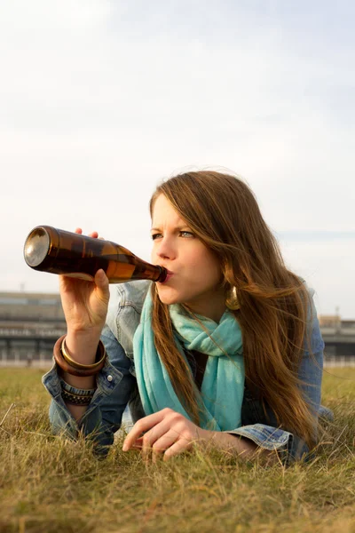 Ragazza che beve una birra guardando il sole — Foto Stock