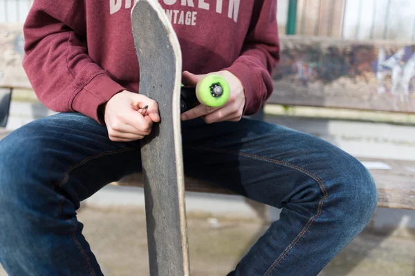 Close-up: Homem consertando seu skate na rua — Fotografia de Stock