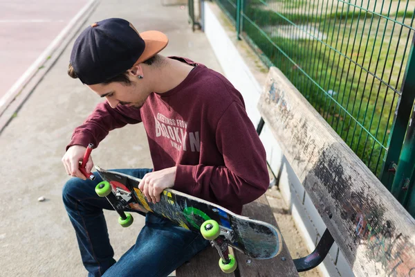 Cara trabalhando em seu skate quebrado — Fotografia de Stock