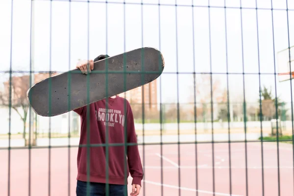 Cara segurando seu skate em um tribunal — Fotografia de Stock