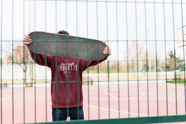 Derrière une clôture avec son Skate — Photo