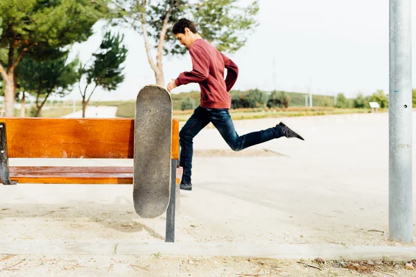 Homem correndo & Skate segurando em um banco de rua — Fotografia de Stock