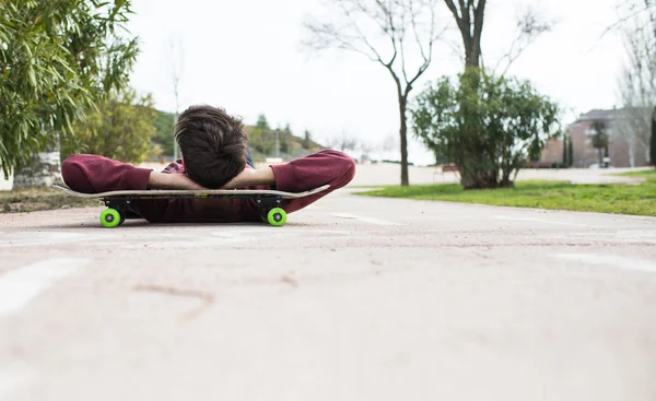 Homem descansando em seu Skate em um caminho de bicicleta — Fotografia de Stock