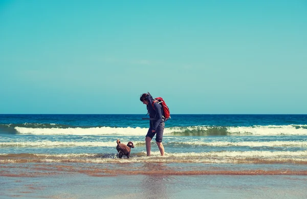 Excursionista paseando en una playa con un perro —  Fotos de Stock