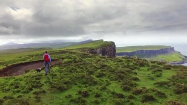 Hiker and dog walking along the cliffs