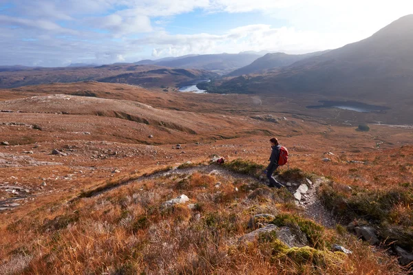 A hiker and dog descending the summit of Beinn Eighe — Stock Photo, Image