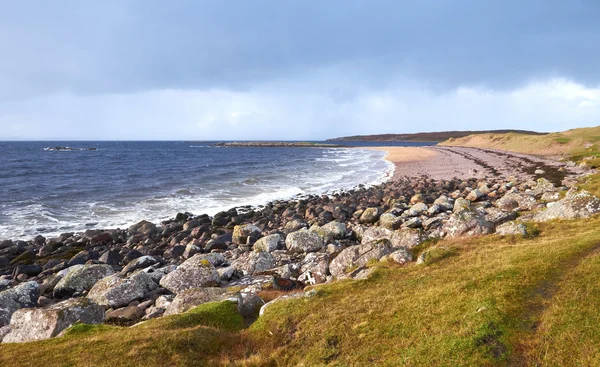 Sista timmen av solen över en avlägsen stenig strand. — Stockfoto