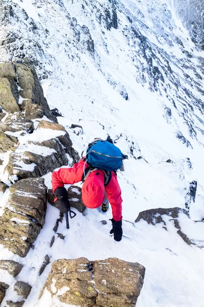 Um alpinista subindo um cume coberto de neve — Fotografia de Stock