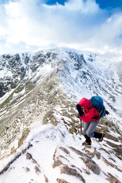 En klättrare stigande en snötäckta ås — Stockfoto