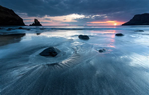 Arena negra y rocas en la orilla del mar — Foto de Stock